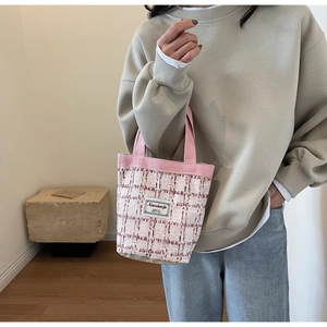 Detail of pink and white checkered tweed tote bag with minimalist logo and textile texture