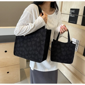 Detail of black heart-patterned tote bag set with textured jacquard fabric shown on model