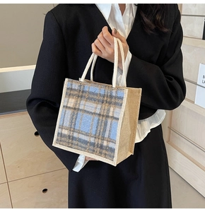 Detail of a plaid linen tote bag featuring a blue and khaki pattern with rope handles