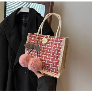 Detail of red and white tweed lunch bag with rope handles and pink cherry charm accessory