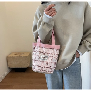 Close-up of pink and white tweed woven bucket bag with elegant fabric handle