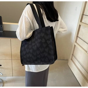 Rear view of model wearing a black heart-patterned canvas tote bag for daily commute