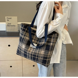 Détail du sac cabas en laine à carreaux avec sangle tissée et étiquette de marque