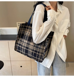 Side view of a blue and beige plaid wool tote bag on a model showing large capacity