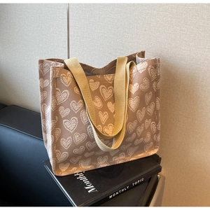 Detailed view of tote bag with white heart jacquard pattern on light brown fabric