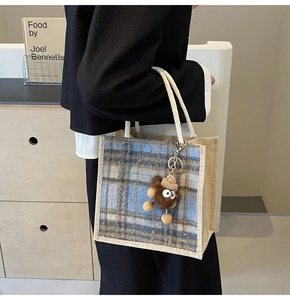 Close-up of checkered linen tote bag with rope handle and plush monster charm decoration