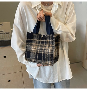 Detailed shot of a plaid wool tote bag with blue fabric handles and metal snap button