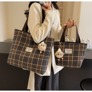 Detail view of large and small brown plaid tote bags with fuzzy monster pendants