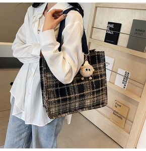 Detail of wool plaid tote bag with wide strap and plush monster charm in library setting