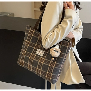 Detail of vintage plaid tote bag with plush charm and large capacity for women