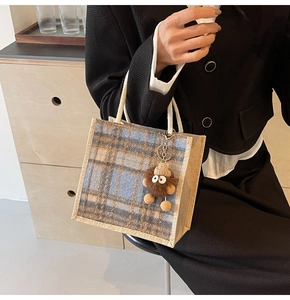 Classic checkered linen tote bag detail with cute plush coal ball charm and woven handle