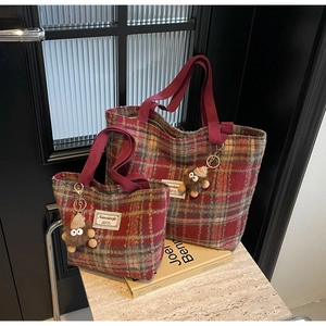 Détail du sac cabas en laine à carreaux rouges avec breloques monstres et étiquettes