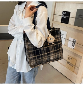 Fashionable dark plaid wool tote bag with plush charm shown in a model's daily use context