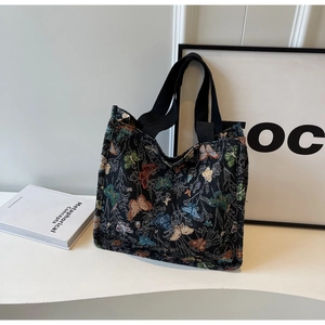 Close-up of colorful butterfly embroidery on a black canvas tote bag with woven texture