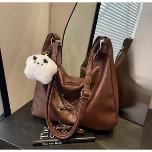 Détail d'un grand sac cabas marron foncé avec laçage croisé et pendentif chien peluche
