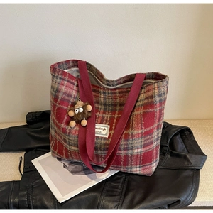 Détail d'un sac cabas en laine à carreaux rouges avec étiquette de marque et porte-clés