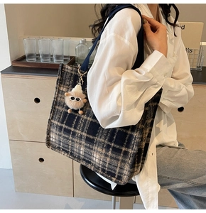 Detail of checkered wool tote bag in navy and tan with a cute plush sheep charm