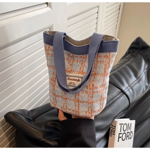 Detail of blue and orange plaid woven bucket bag with white decorative fabric label