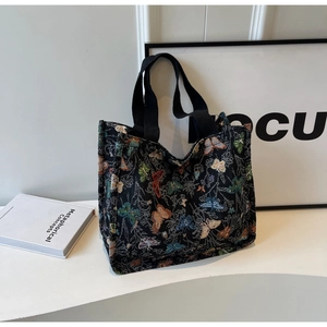 Detail of colorful butterfly embroidery on black canvas tote bag with woven handles