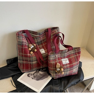 Détail de sacs cabas à carreaux rouge et gris avec pendentifs sur une veste en cuir