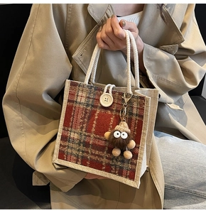 Detail of red checkered linen handbag with woven rope handle and brown plush charm