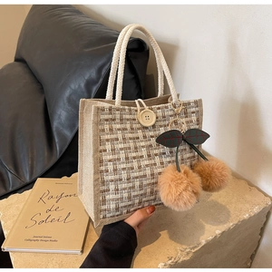 Détail du sac à lunch en lin tissé avec poignées en corde blanche et pompons cerise
