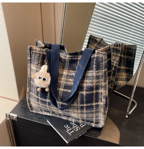 Close-up of navy and beige plaid wool tote bag with a cute plush monster charm detail