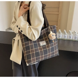 Detail of vintage plaid canvas tote bag with shoulder strap and plush ball pendant charm