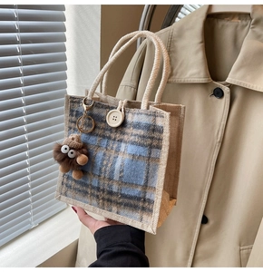 Detail of checkered linen tote bag with cream rope handles and brown monster pendant
