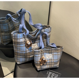 Détail de sacs cabas à carreaux en laine bleu et marron avec breloques peluche sur miroir