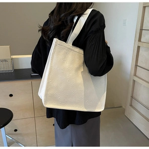 White heart-embossed tote bag side view showing 3D textured fabric and strap details