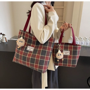 Detail showing two sizes of checkered canvas tote bags with red handles and plush charms