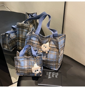 Close-up of wool plaid tote bag set in blue and brown with plush monster charms