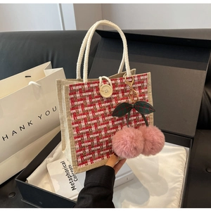 Détail d'un sac bento en lin à carreaux rouge et blanc avec bouton en bois et cerises