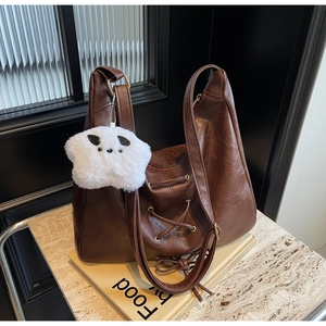 Détail d'un sac cabas marron foncé avec laçage croisé et un pendentif étoile en peluche
