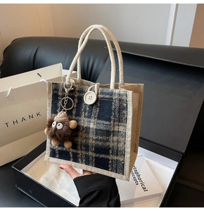 Close-up of checkered linen tote with cotton rope handles and a plush monster charm