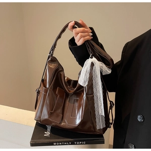 Détail du sac bandoulière en cuir verni marron café avec broderie numéro 10 et nœud dentelle