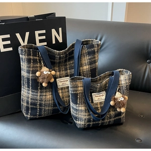 Détail de grands et petits sacs cabas à carreaux avec pendentifs en peluche sur canapé