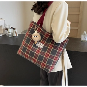Detail of red and grey plaid canvas tote bag with shoulder strap and plush charm