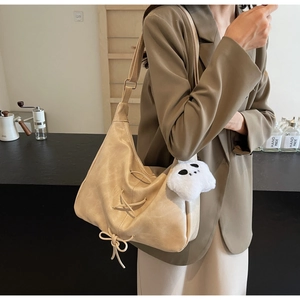 Détail du sac fourre-tout beige en similicuir avec nœud et pendentif ours sur le mannequin