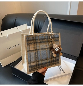 Close-up of linen plaid handbag in gift box with cute lion charm and soft lighting