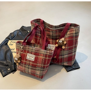 Détail de sacs cabas en laine à carreaux rouge et vert avec charm monstre en peluche