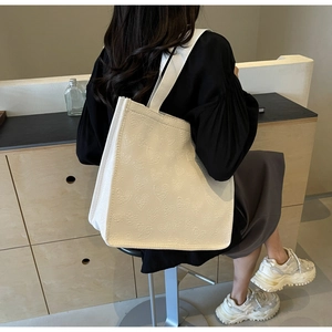 Detail of cream white tote bag featuring 3D heart embossing and wide fabric shoulder strap