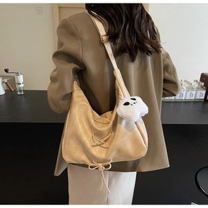 Détail du grand sac cabas en cuir souple beige avec lanières croisées et breloque
