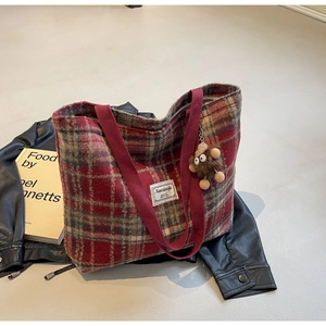 Détail du sac cabas à carreaux en laine avec breloque singe et étiquette de marque sur cuir
