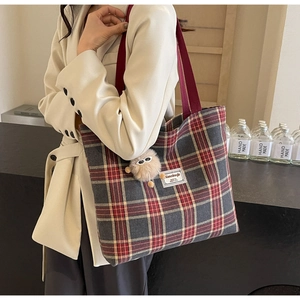 Detail of red and black plaid canvas tote bag featuring a cute plush eyewear charm