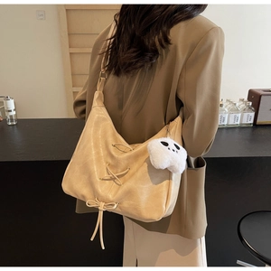 Détail du sac cabas crème en cuir avec laçage latéral et breloque fantôme en peluche