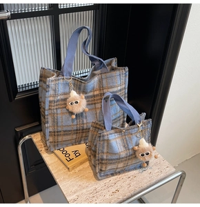 Detail view of two checkered wool tote bags with blue handles and plush toy charm