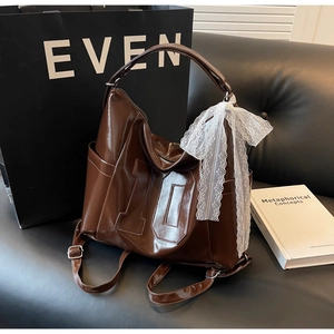 Détail du sac à bandoulière en cuir brillant marron avec nœud en dentelle et chiffre 10