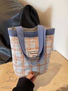 Blue and white tweed bucket bag with orange plaid lines and purple woven handle